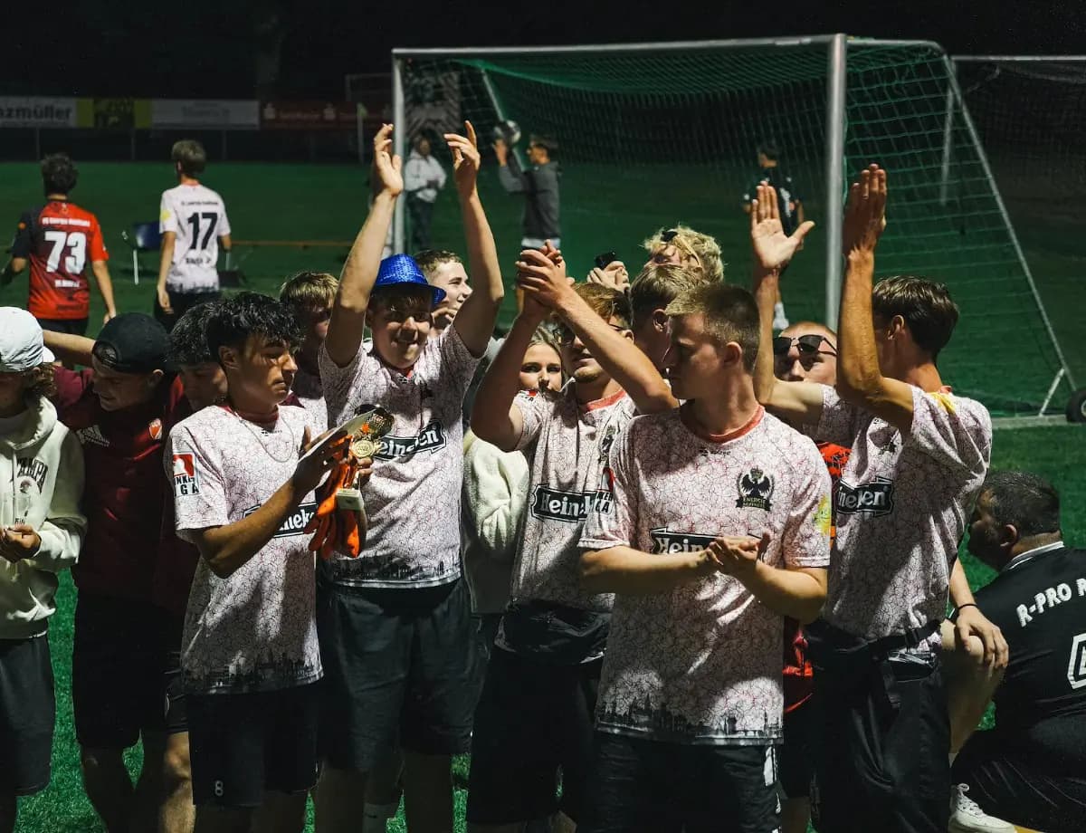 Ein Team feiert mit dem Pokal, Arme in der Luft