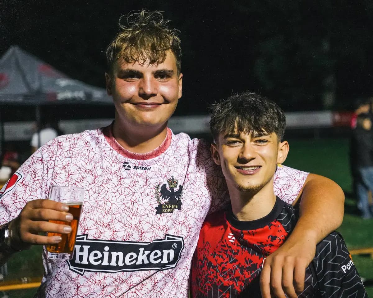 Zwei Spieler stoßen mit Bechern an und lachen