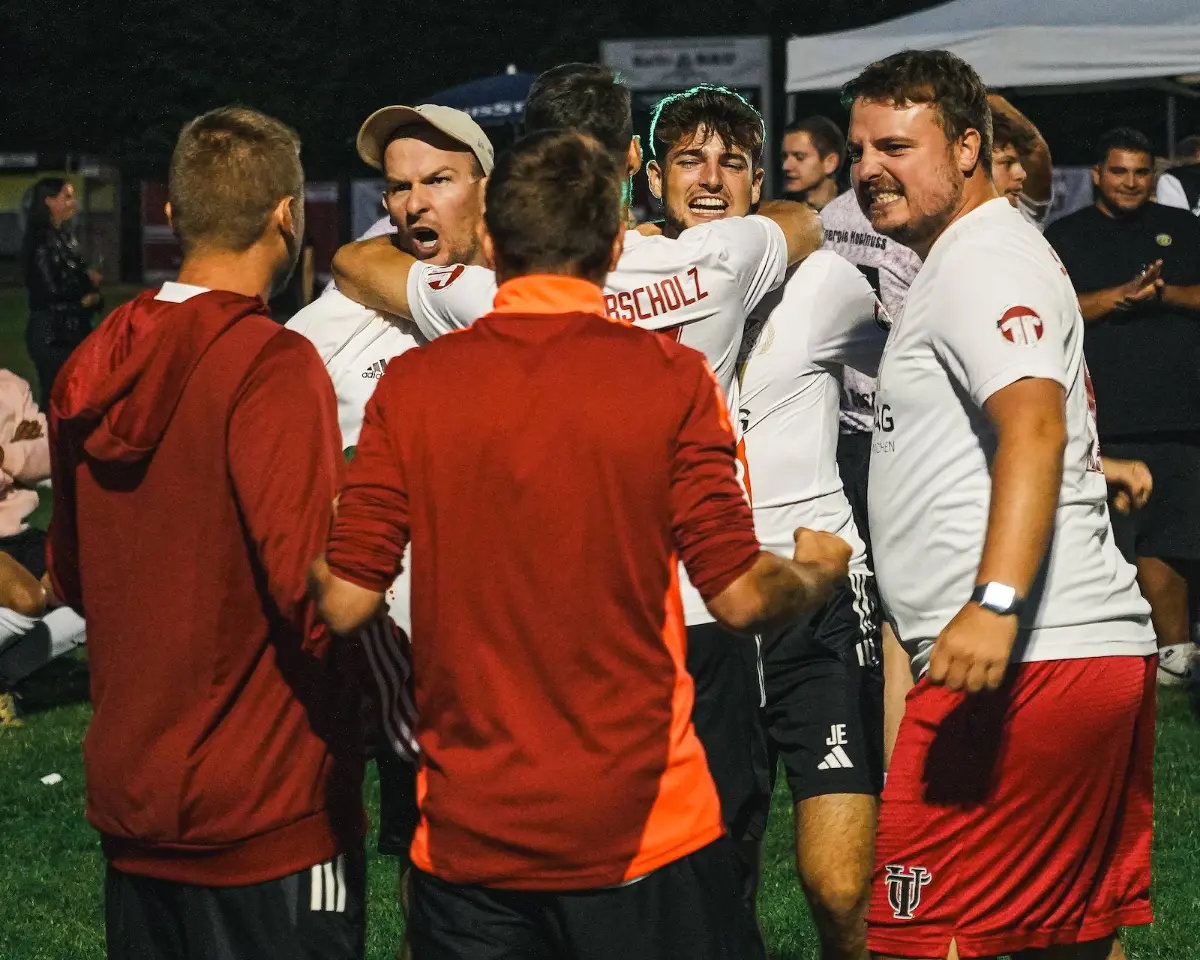 Vier Spieler in orangefarbenen Trikots stehen zusammen