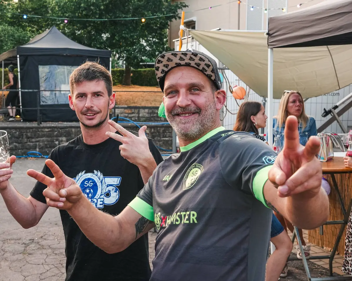 Zwei Männer stehen nebeneinander, einer mit Kappe