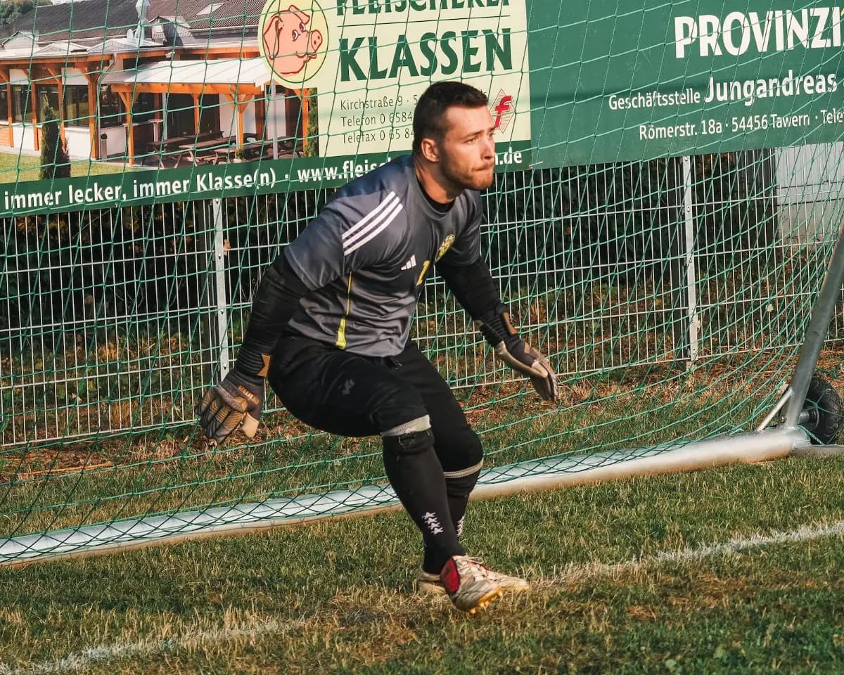 Ein Torwart in dunklem Trikot macht sich bereit