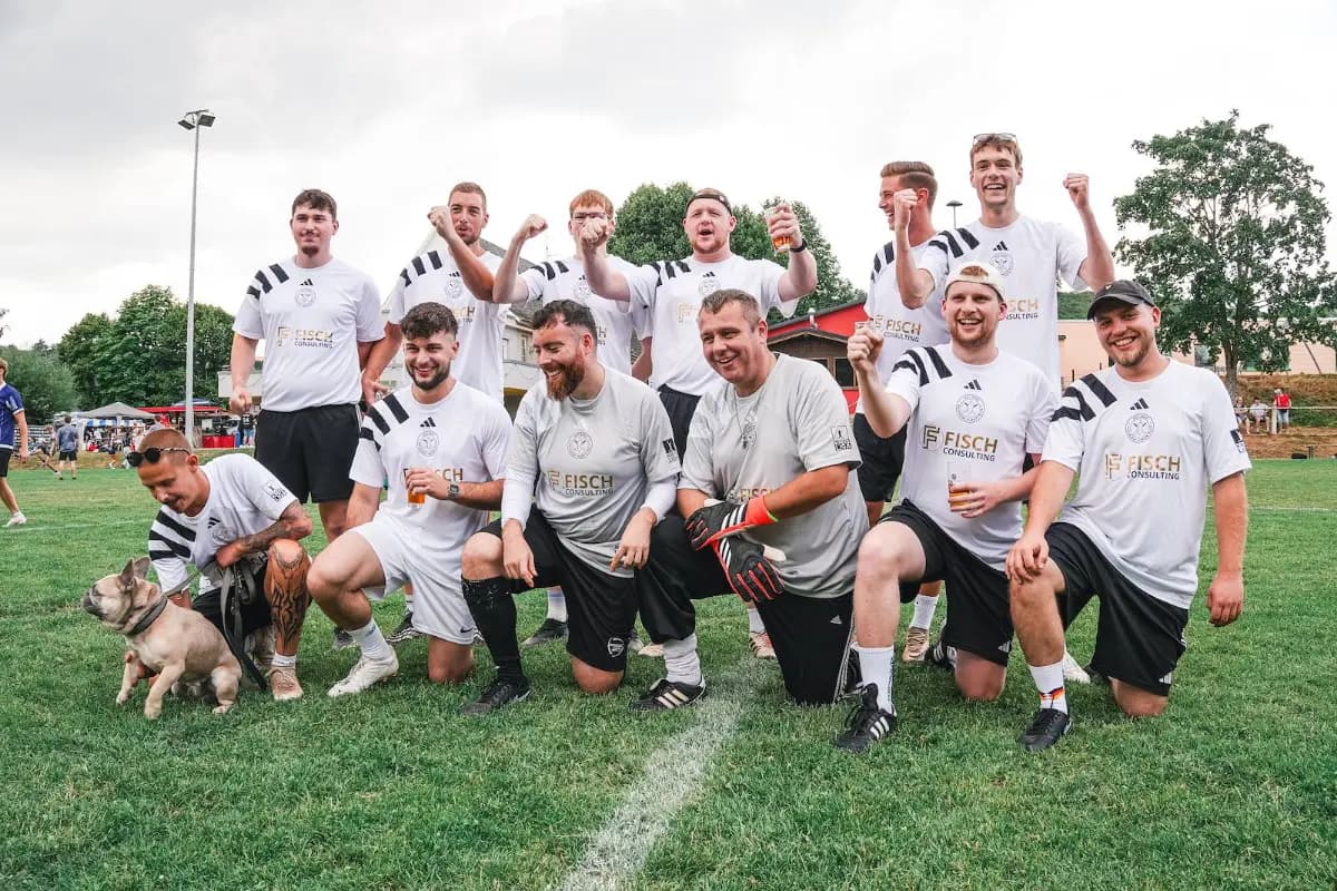 Ein Team feiert im Gras vor dem Tor