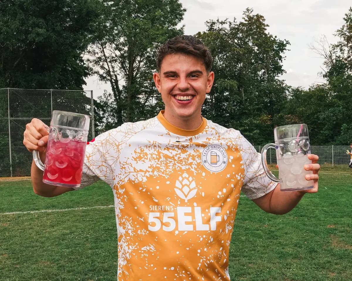Ein Spieler in orangefarbenem Trikot hebt seinen Becher