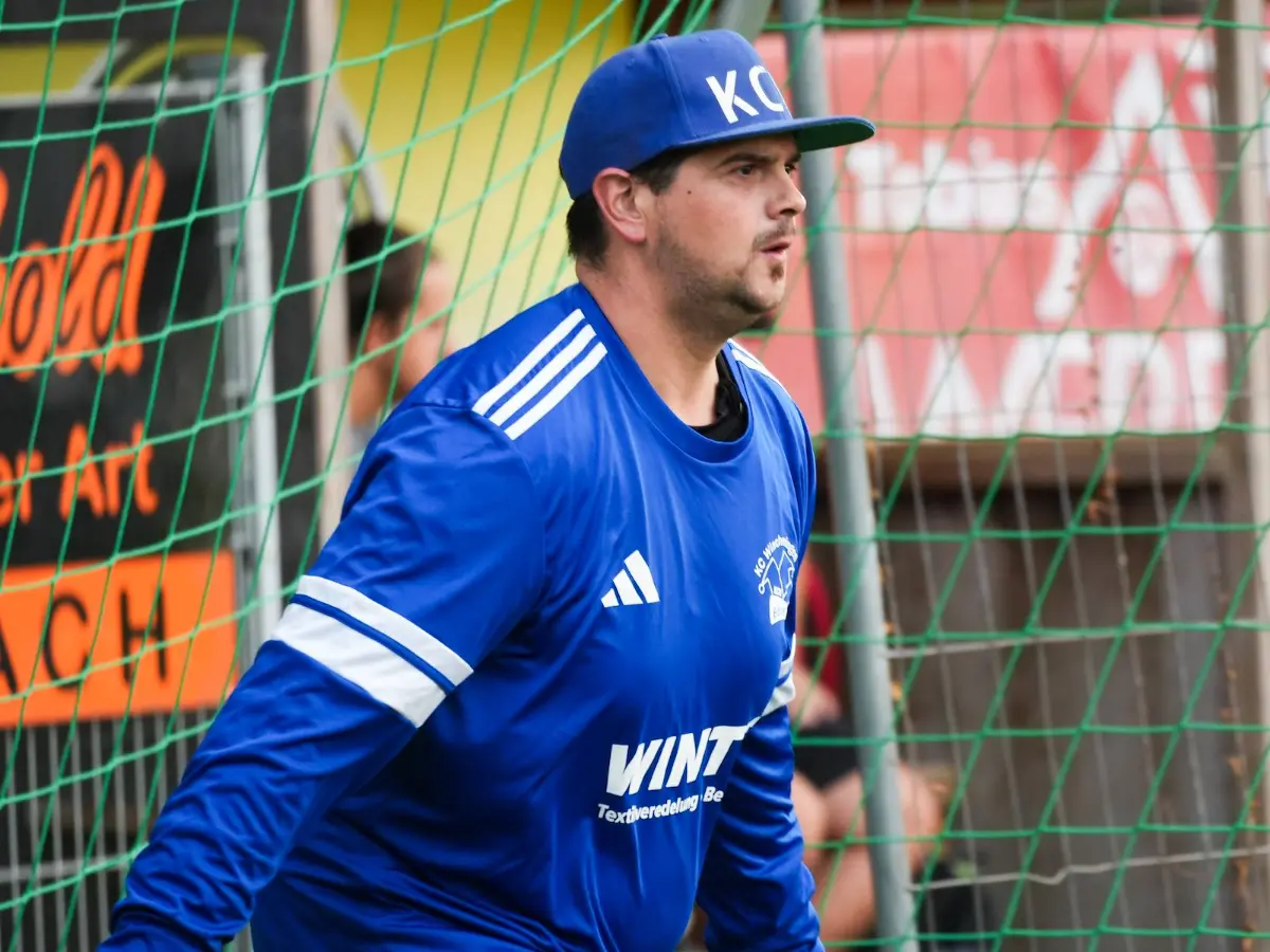 Ein Torwart in Blau vor der roten Bande