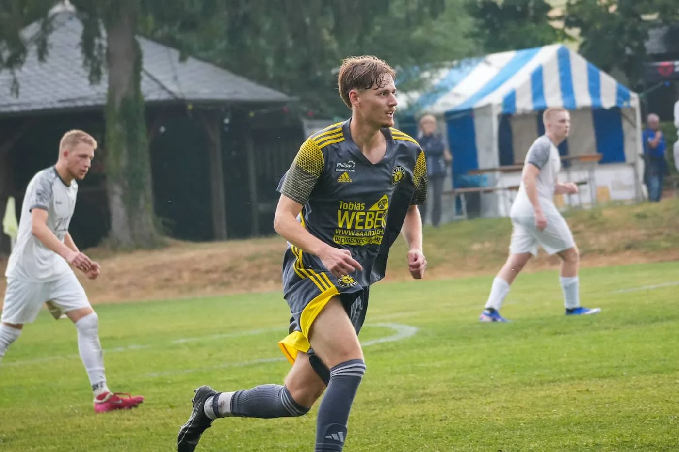 Ein Spieler führt den Ball, hinter ihm das Festzelt am Sportplatz