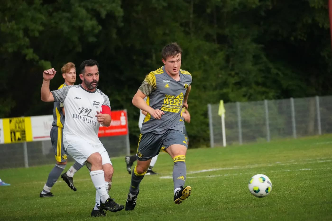Ein Spieler in Grau-Gelb setzt sich gegen einen Gegner in Weiß durch