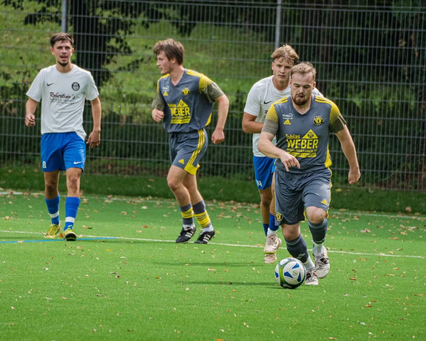 Drei Spieler laufen dem Ball entgegen